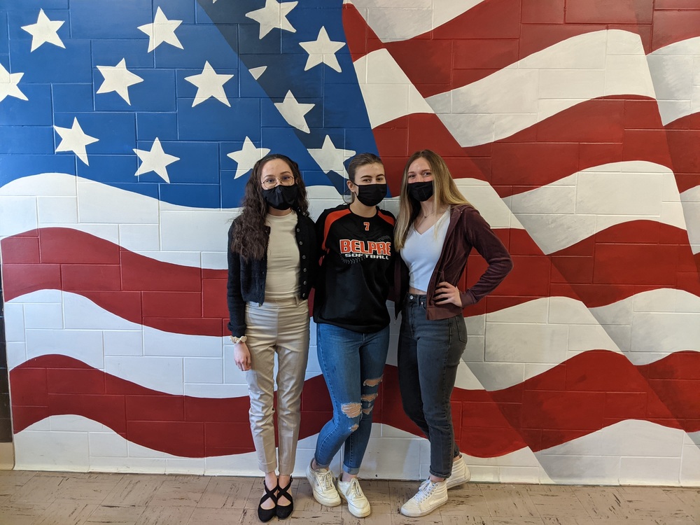  3 girls standing in front of a flag painting