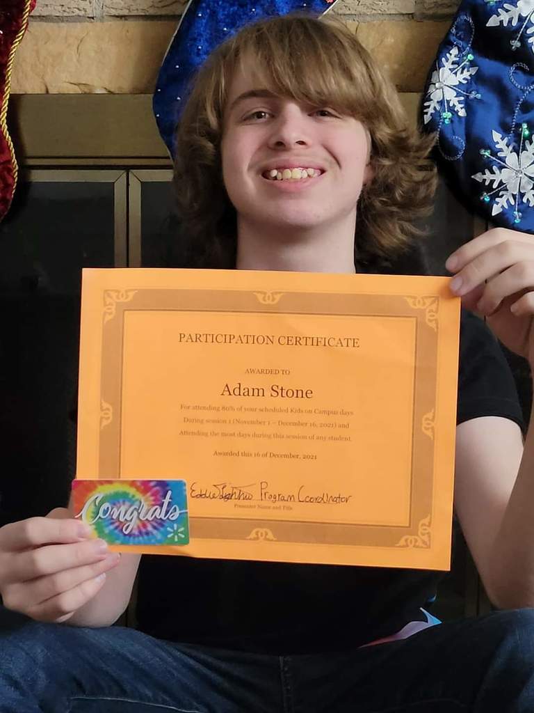 Adam Stone proudly displaying his certificate and gift card for participation in the Kids on Campus after-school program